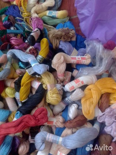 Много ниток и канвы для вышивки